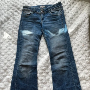 Blå jeans från Gina Tricot - Snygga blå jeans från Gina Tricot med en klassisk femficksdesign och dubbla knappar i midjan. Perfekta för en avslappnad stil med en lätt tvättad look. Passar bra till både sneakers och kängor.