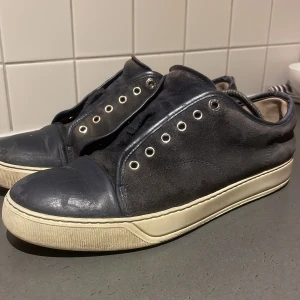 Mörkblå sneakers - Snygga mörkblå sneakers i mocka från lanvin, de är välanvända men ser fortfarande bra ut. Bakdelen av skon är sliten och underdelen av framdelen. Strlk 9/42. Har inte kvar original sulorna, kvitto är det ända som följer med