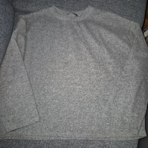 Grå tröja från Zara - Säljer en stilren grå tröja från Zara. Tröjan har en enkel design med rund hals och långa ärmar, perfekt för en avslappnad look. Den är mjuk och bekväm, idealisk för kyligare dagar.