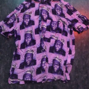 Lila kortärmad skjorta från H&M Biggie, Notorious BIG - Säljer en cool lila skjorta från H&M med korta ärmar och ett unikt mönster. Skjortan har knappar framtill och är perfekt för dig som vill sticka ut. Passar bra till både jeans och shorts!