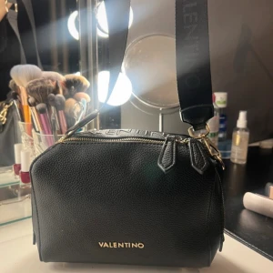 Svart axelväska  - Snygg svart axelväska från Valentino i skinn med guldfärgad dragkedja. 