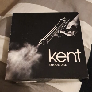 Kent Box 1991-2008 - Säljer en exklusiv Kent Box 1991-2008 med 10 CD-skivor inklusive alla album och 26 bonusspår. Boxen innehåller även en 96-sidig bok med intervjuer och bilder. Perfekt för Kent-fans som vill ha hela samlingen i ett stilrent format.