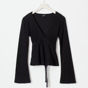 Svart v ringad topp - Snygg svart topp med v-ringning och långa ärmar. Toppen har en knytning i midjan som ger en fin passform. Perfekt för en stilren look.