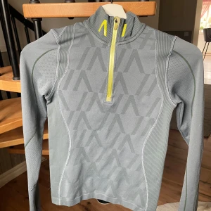 Grå långärmad tröja med dragkedja från All in - Snygg grå långärmad ridtröja med halv dragkedja från All in i storlek XS. Använd några fåtal ggr. Jättefint skick. 