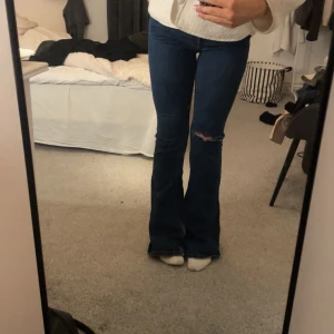 Blå bootcut jeans - Snygga blå bootcut jeans med ett hål på ena benet. Har dock en liten slitning på rumpan, men går nog att sy själv eller lämna in hos skräddaren!