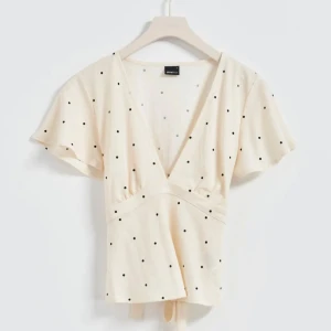 Prickig topp - Såå gullig topp från Gina tricot! Den är ljus ljus begie och har en knytning i ryggen som även går att ha framåt. Den är i mycket bra skick!☺️Köpte den av en tjej på plick för 400kr så de därför jag säljer den för så mycket. 