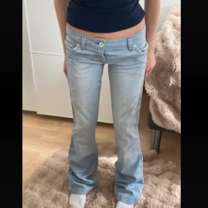 Ljusblå bootcut jeans - Snygga ljusblå bootcut jeans med låg midja och klassisk femficksdesign. Perfekta för en avslappnad stil. De har en dragkedja och knapp framtill. Midjemått 37 cm tvärsöver, Innerben 83