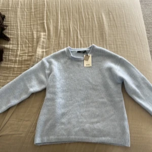 Ljusblå stickad tröja från Bik Bok - Säljer en ljusblå stickad tröja från Bik Bok i återvunnen polyesterblandning. Tröjan har en klassisk rund hals och långa ärmar, perfekt för kyligare dagar. Enkel och stilren design som passar till det mesta. 🌟Aldrig använd och köpt någonstans i februari, säljer pga för liten. Pris kan absolut deiksuteras och kom privat för fler bilder!