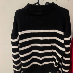 Svart och vit randig stickad tröja - Säljer en snygg svart och vit randig stickad tröja med långa ärmar. Perfekt för kyligare dagar med sin mjuka och bekväma passform. Tröjan har en klassisk design som passar till det mesta. Endast använd fåtal gånger 