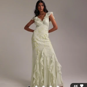 Ljusgrön långklänning med volanger - Säljer denna superfina ljusgröna långklänning med v-ringning och blommiga broderier. Har volanger även volanger nertill. Från ASOS och helt oanvänd med prislapp kvar