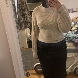 Beige stickad tröja från Lindex - Säljer en snygg beige stickad tröja från Lindex. Tröjan har en croppad design och långa ärmar, perfekt för en stilren look. Den är ribbad vilket ger en fin textur och passform.