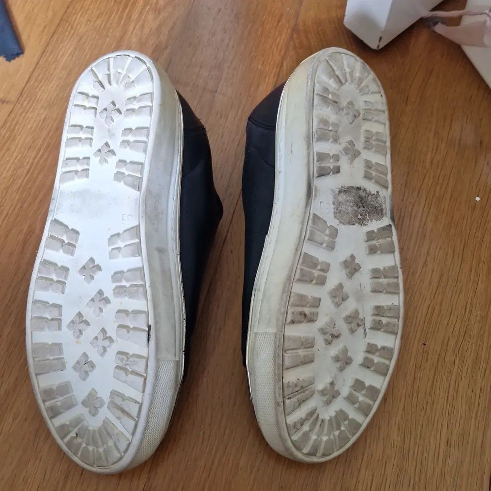 Snygga svarta sneakers med en elastisk detalj framtill för enkel på- och avtagning. Skorna har en vit sula och är tillverkade i syntetmaterial. Perfekta för en avslappnad stil.. Kengät.