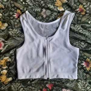 Vit ftm binder med dragkedja - Säljer en vit binder med dragkedja framtill. Bindar bra. Mjukare tyg och dragkedjan ger extremt enkel av och påtagning, så den är perfekt när man vill binda lite casually eller när det är varmt:) passar strl S-xS. Bra men använt skick!