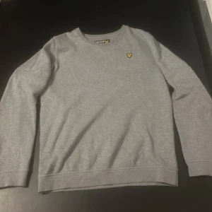 Grå tröja från Lyle & Scott - Säljer en grå tröja från Lyle & Scott med den klassiska gula fågeln broderad på bröstet. 