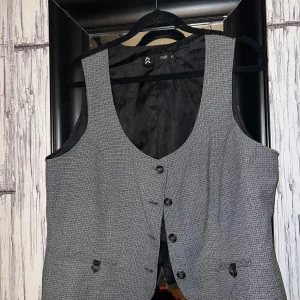 Grå väst från Prét - Snygg grå väst från Prét med knappar framtill. Perfekt för att ge en stilren touch till din outfit. Västen har en klassisk design och är lätt att matcha med olika plagg.