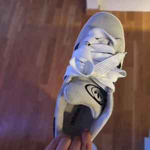Adidas Campus sneakers - Snygga Adidas Campus sneakers i vitt med svarta ränder och klassisk gummisula. Väl använda men ändå  ok i skick