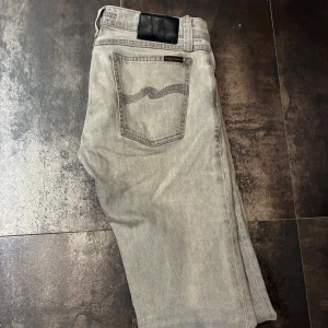 Grå jeans från Nudie Jeans - Snygga grå jeans från Nudie Jeans med en klassisk femficksdesign. De har en smal passform och är tillverkade i ett bekvämt denimtyg. Perfekta för en stilren look.