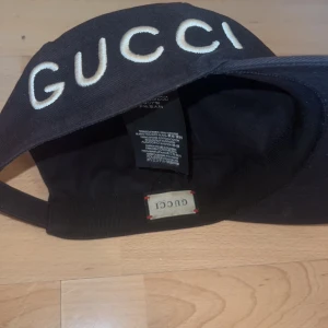Svart keps från Gucci( Limited edition)  - Snygg svart keps från Gucci med texten 'GUCCI' broderad framtill och 'LOVED' på sidan. Kepsen är tillverkad i bomull och har en justerbar rem baktill för perfekt passform. Den är limited edion och går inte att få tag på längre. Köpt för 5000, säljer för 2500. Pris kan diskuteras vid snabb affär, kan posta mötas upp.