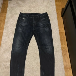 Disel jeans - Snygga svarta jeans från Diesel med klassisk femficksdesign och diskreta slitningar. Perfekta för en stilren look. Märkesdetaljer syns på fickan och bak i midjan.