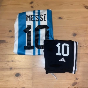 Messi Argentina tröja och shorts - Säljer min Argentina fotbollströja med korta ärmar och blåvita ränder, samt svarta shorts till. Kläderna är i bra skick. Jag är villig att sänka priset!