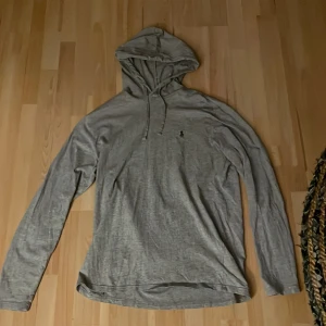 Grå hoodie från Ralph Lauren - Säljer en stilren grå hoodie från Ralph Lauren med det klassiska logotypbroderiet på bröstet✔️🤩Tröjan har en bekväm passform med långa ärmar och en justerbar huva med dragsko, Perfekt för sommar och hösten sedan allmänt för en fett och avslappnad look💸🍾 (Priset för att diskuteras)