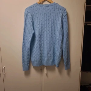 Ljusblå stickad tröja från Ralph Lauren - Säljer en stilren ljusblå stickad tröja från Ralph Lauren. Helt ny och oanvänd.