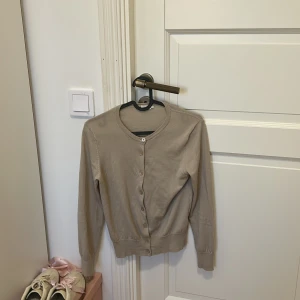 Beige kofta från Filippa K - Säljer en stilren beige kofta från Filippa K i storlek XS. Koftan har långa ärmar och knappar framtill, perfekt för lager på lager-stil. En klassisk och tidlös design som passar till många tillfällen. Nypris ca 2500🩷 pris går att diskutera💞💞