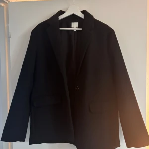 Svart kavaj från H&M - Snygg kavajjacka från H&M. Använd en gång. Säljer då den inte kommer till användning 