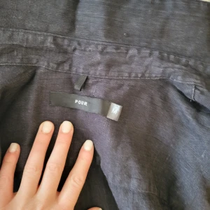 Mörkblå linneskjorta från Pour - Säljer en stilren mörkblå skjorta från Pour i linne. Skjortan har långa ärmar och knappar framtill. Perfekt för en avslappnad men ändå uppklädd look. Passar bra till både jeans och chinos.