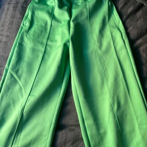 Gröna byxor från SOC - Snygga gröna byxor från SOC med elastisk midja för extra komfort. Byxorna har en rak passform och är perfekta för en avslappnad stil. Tillverkade i ett mjukt material lite mer åt träningskläder. Stängbara fickor på sidorna, lite insydda i midjan som är lätt att sprätta upp. Använda 1 gång.