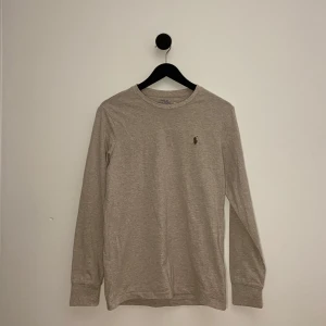 Ralph Lauren Tröja - Säljer en stilren beige långärmad tröja från Polo Ralph Lauren. Tröjan har en broderad logotyp på bröstet och är i en slim fit passform. Perfekt för en avslappnad men ändå snygg look.