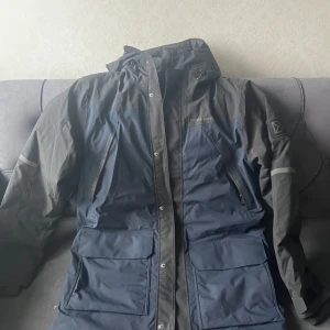 Vinterjacka  Didriksons  - Säljer en svart och blå jacka från Didriksons med Stormsystem för 100% vattentät, vindtät och …. . Perfekt för kalla och blöta dagar.( Priset kan diskuteras).