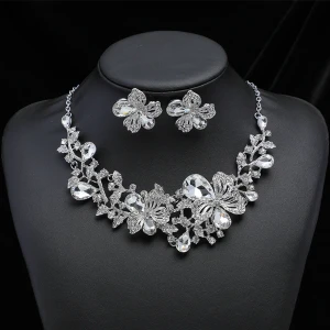 Blomformade silverfärgade smycken - Elegant halsband och örhängen i silverfärg med blommotiv och glittrande stenar. Halsbandet har en justerbar kedja och matchande örhängen med samma blommönster. Perfekt för att ge en gnistrande touch till din outfit.