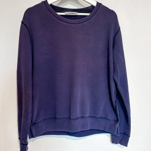 lila tröja från Acne Studios - Mysig jumper från acne studios! Den har varit älskad, men jag har tröttnat på färgen :) Blir glad om någon annan kan få älska den nu. Har en trevlig detalj med svarta remmar sydda längs sidan.   Jag skulle inte säga att den har några tydliga defekter, och färgen i sig är lite gjord för att se använd ut, men den är absolut använd mycket - därav min indelning på plaggskick.   Strl S, sann i storleken. Notera att den är lite croppen och att den inte är sydd längs med hela midjepartiet. 