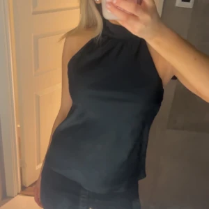 Svart halterneck-top - Snygg svart halterneck-top med hög hals och ärmlös design. den är öppen i ryggen och det finns en dragkedja där också🥰