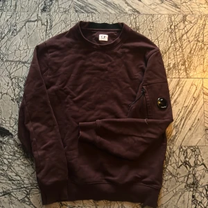 Mörklila tröja från C.P. Company - Säljer en snygg mörk röd tröja från C.P. Company. Tröjan är i bra skick, den kostar ca 2300 ny och säljs för 350