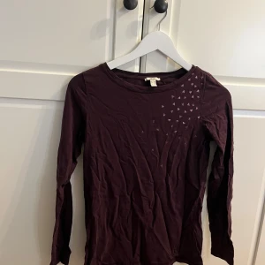 Mörklila långärmad topp från EDC - Säljer en mörklila långärmad topp från EDC med små triangulära detaljer på framsidan. Perfekt för en stilren look. Toppen är i ett mjukt och bekvämt material.