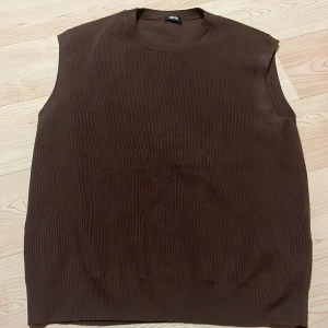 Väst från Uniqlo - Säljer en stilren brun ärmlös topp från Uniqlo. Toppen har en ribbad textur och rund halsringning, perfekt för lager-på-lager eller som den är. Passar till många olika stilar och tillfällen. XS/S/m 