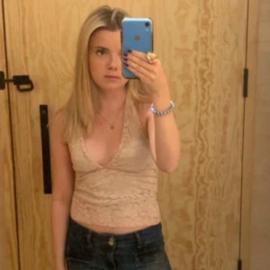 Spets topp - Säljer ett snyggt beige spetslinne med djup v-ringning och smala axelband. Perfekt för en somrig look eller en utekväll. Linnet har ett vackert blommönster.