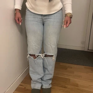 Ljusa jeans med slitningar - Snygga ljusblå jeans med slitningar vid knäna. De har en klassisk femficksdesign och en bekväm passform. Perfekta för en avslappnad stil.