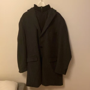 Svart kappa från Erla of Sweden - Elegant svart kappa från Erla of Sweden. Den har en klassisk design med långa ärmar och en stilren krage. Perfekt för kyligare dagar men även tillräckligt luftig för något varmare dagar. Perfekt för vinter, vår och höst.