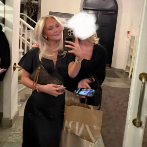 Svart långklänning med v-ringning - Elegant svart långklänning i satin med v-ringning och kortärmad design. Perfekt för en stilren look. Endast använd en gång