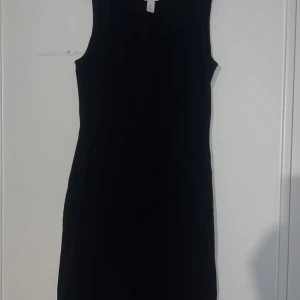 Svart ärmlös klänning från H&M - Snygg svart ärmlös klänning från H&M. Perfekt för en stilren look. Klänningen har en enkel design som gör den lätt att matcha med olika accessoarer.