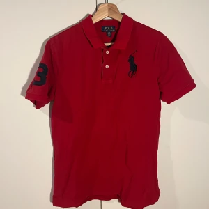Röd pikétröja från Polo Ralph Lauren - Säljer en snygg röd pikétröja från Ralph Lauren med klassisk krage och knappar då den inte används. Perfekt nu till varmare väder och sommaren. Mitt pris: 99 kr