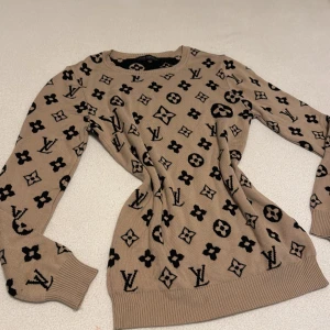 Beige tröja från Louis Vuitton - Säljer en snygg beige tröja från Louis Vuitton med deras ikoniska monogrammönster i svart. Tröjan har långa ärmar och är tillverkad i en mjuk viskosblandning. Perfekt för dig som vill ha något stilrent och lyxigt i garderoben.