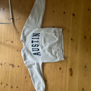 Beige sweatshirt AUSTIN Gina Tricot XS - Snygg beige sweatshirt från Gina Tricot i storlek XS med trycket 'AUSTIN' i mörkblå bokstäver på framsidan. Tröjan har rund hals, långa ärmar och ribbade muddar. Perfekt för en chill och avslappnad stil. Tröjan har en del fläckar som inte går bort i tvätten.