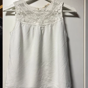 Vit ärmlös blus med spets H&M - Säljer nu denna vita blus från H&M i storlek 164, men storleksmässigt är den XS/liten S. Jag är 171 och tycker nu att den är lite för liten vid axlarna. Toppen är ärmlös och har en vacker spetsdetalj upptill med broderade blommor. Kan skicka fler bilder! 