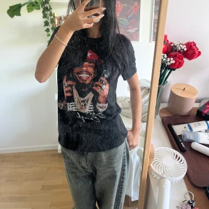 Svart t-shirt med stor grafisk print - Svart t-shirt med coolt grafiskt tryck framtill. Perfekt för dig som gillar streetstyle och statement-plagg. Storlek är M men skulle säga att det passar S bättre