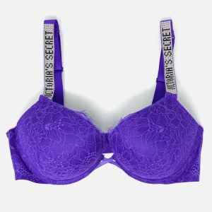 Lila spets-bh från Victoria's Secret - Superfin lila bh från Victoria's Secret med blommig spets och glittriga axelband där det står 'Victoria's Secret'. Axelbanden är dekorerade med strass och bh:n har en snygg formad kupa. Perfekt för dig som vill ha något extra under outfiten.
