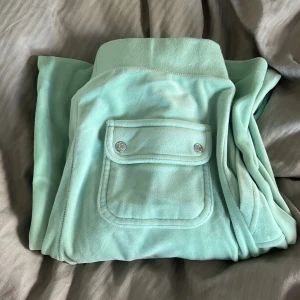 Mintgröna mjukisbyxor Juicy Couture  - Supermjuka mintgröna mjukisbyxor från Juicy Couture med bred resår i midjan, snörning och fickor fram. Bakficka med lock och silverfärgade knappar. De är supersköna och de är knappt använda! Pris kan diskuteras vid snabbt köp
